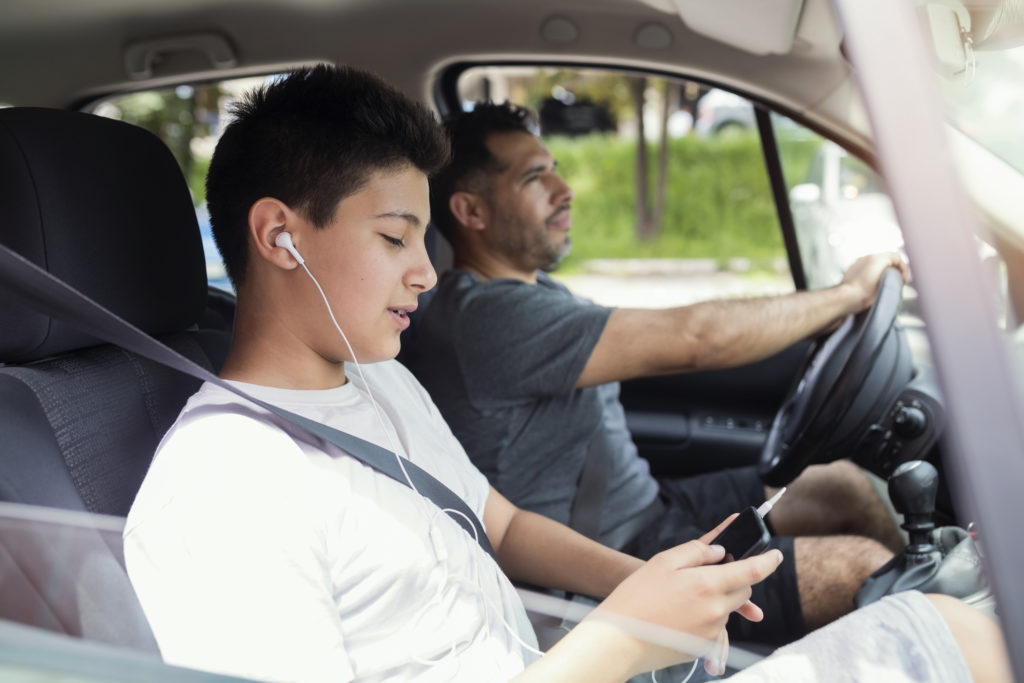 boy using phone while father drives car